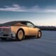 Coche eléctrico futurista recorriendo un paisaje nevado al atardecer en un entorno frío y tranquilo.